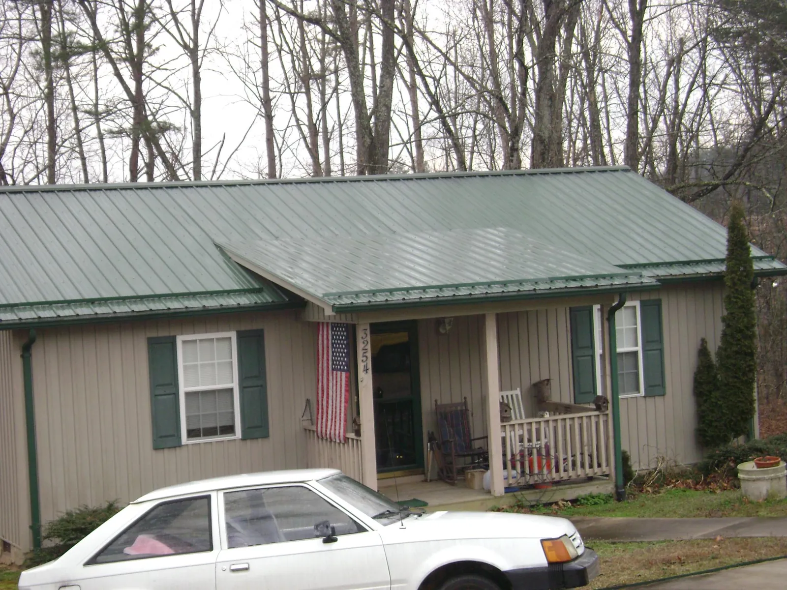 Green metal roof and front porch on a tan sided cottage in Edwards
