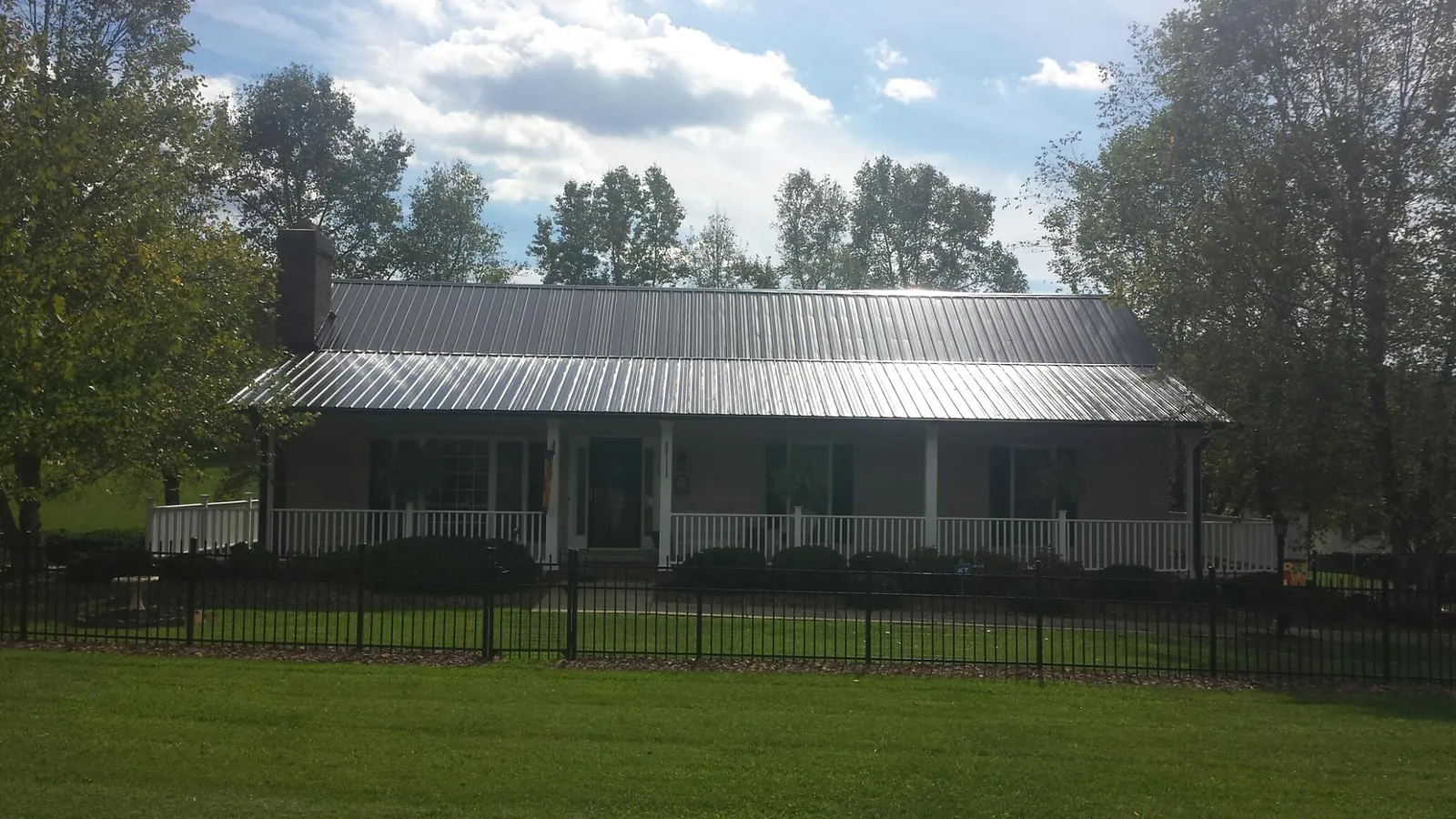 Gray metal roof on a brick ranch with a full width front porch — Gutter Guard Installation work by our crew in Edwards