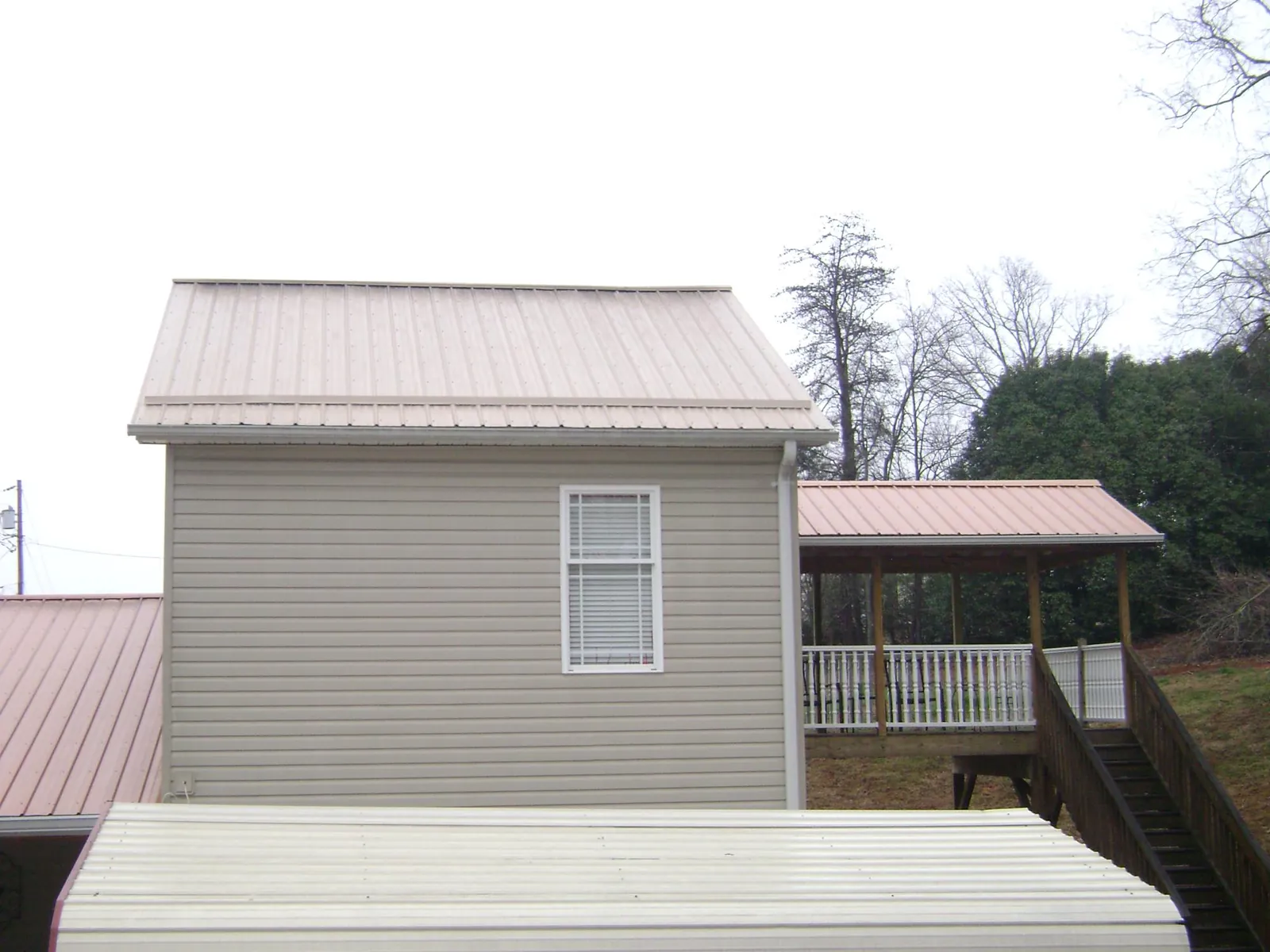 Tan metal roofs on a two story addition and attached porch, from a Roof Replacement job in Edwards
