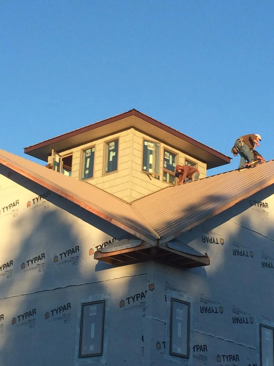Roofers working around a rooftop cupola on a new metal roof at sunset — Roof Waterproofing in Edwards by Roofing Brothers